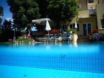 a swimming pool with two chairs and an umbrella at Hotel Stampfer B&B in Laives