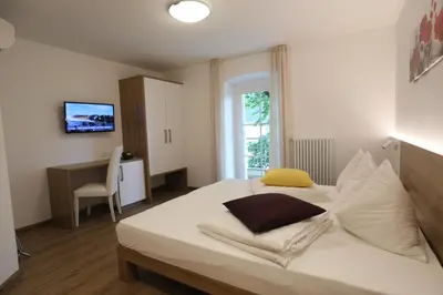 a bedroom with a large white bed and a desk at Hotel Stampfer B&B in Laives