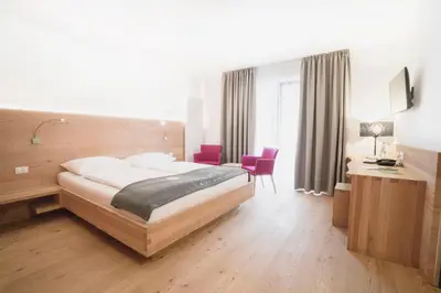 a hotel room with a bed and a desk and chairs at Vegan Hotel La Vimea in Naturno