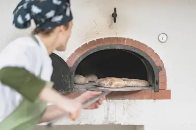 a man baking bread in a brick oven at Vegan Hotel La Vimea in Naturno