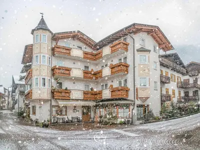 a large building with snow falling on it at Hotel Siror in Fiera di Primiero