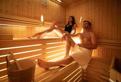 a man and a woman sitting in a sauna at Hotel Siror in Fiera di Primiero