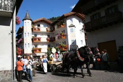 a horse pulling a cart in front of a building at Hotel Siror in Fiera di Primiero