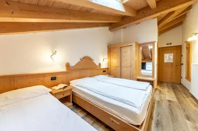 two beds in a room with wooden walls and wooden floors at Hotel Siror in Fiera di Primiero