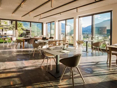 a restaurant with tables and chairs and large windows at Garni Hotel Katzenthalerhof in Lana