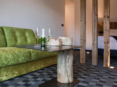a table with wine glasses and a green couch at Garni Hotel Katzenthalerhof in Lana