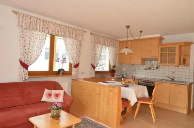 a kitchen and living room with a table and a couch at Villa Paröis in La Valle