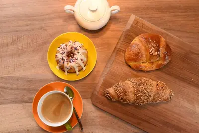 a table with two plates of pastries and a cup of coffee at Frühmesserhaus Refugium zu Sanct Kassian in Lagundo