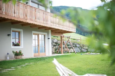 a white house with a balcony and a yard at Ferienwohnung - THOLER in Lagundo