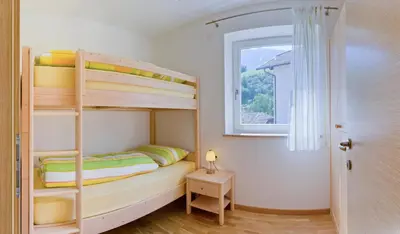 a small bedroom with bunk beds and a window at Ferienwohnungen St. Michael in Appiano sulla Strada del Vino
