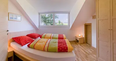 a bedroom with a bed with red pillows and a window at Ferienwohnungen St. Michael in Appiano sulla Strada del Vino