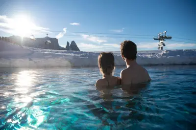 a man and a woman sitting in the water at Hotel Santner Alpine Sport & Relax in Alpe di Siusi