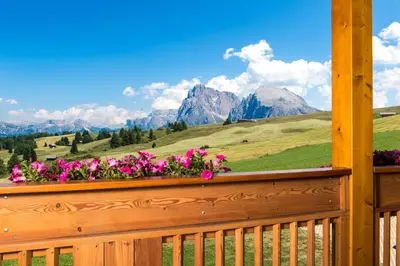 a view of mountains from a porch with flowers at Hotel Santner Alpine Sport & Relax in Alpe di Siusi