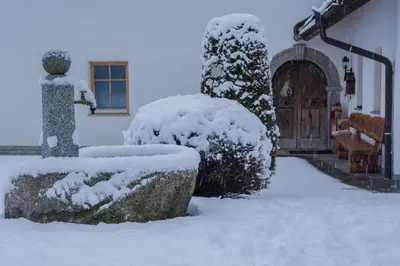 a snow covered yard with a house with a door at Stockerhof in San Lorenzo di Sebato