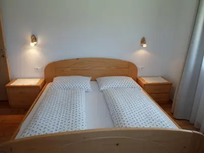 a bedroom with a wooden bed with two night stands at Stockerhof in San Lorenzo di Sebato