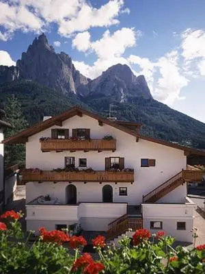 a white building with flowers in front of a mountain at Residence Kampidell in Siusi