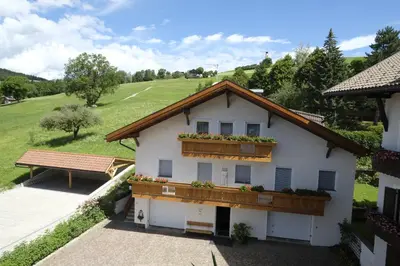 a white house with a balcony and a bench at Residence Kampidell in Siusi