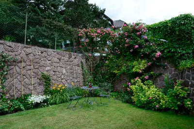a garden with a table and chairs and a stone wall at Residence Kampidell in Siusi