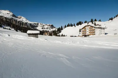 a snow covered field with a building in the background at Apparthotel Sellaronda in Arabba
