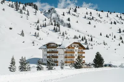 a field of grass with a building in the background at Apparthotel Sellaronda in Arabba