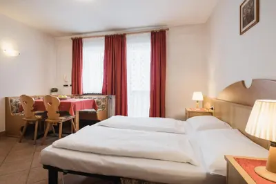 a hotel room with a large bed and a table at Apparthotel Sellaronda in Arabba