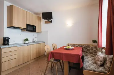 a living room with a table and a kitchen at Apparthotel Sellaronda in Arabba