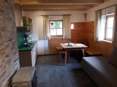 a small kitchen with a table and a table and a couch at Brünnl's Försterhütte in Parcines
