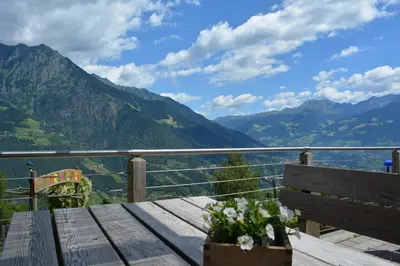 a wooden bench sitting on a table with a view of mountains at Brünnl's Försterhütte in Parcines