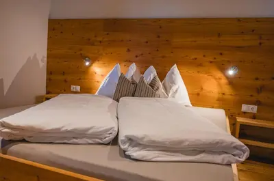 two beds in a room with a wooden wall at Brünnl's Försterhütte in Parcines