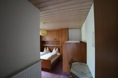 a small room with two beds and a chair at Boarhof Appartaments in San Giacomo Val di Vizze