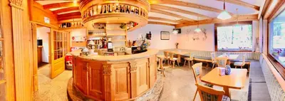 a restaurant with a bar in the middle of a room at Hotel B&B Lorenzini Ski in Selva di Cadore