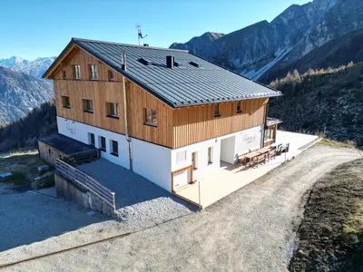 a house on a hill with mountains in the background at Edelweisshütte Ladurns in Fleres