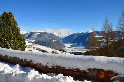 a rail covered in snow with mountains in the background at Apartments Oberpichlhof in Valdaora