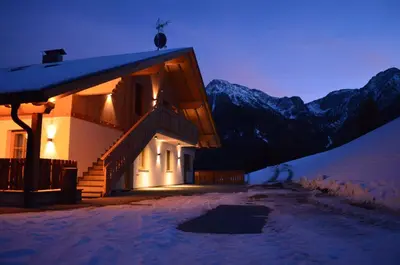 a house in the snow at night with mountains at Apartments Oberpichlhof in Valdaora