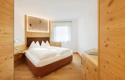 a bedroom with a bed with white sheets and a window at Apartments Oberpichlhof in Valdaora
