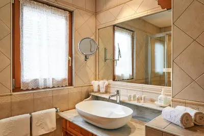 a bathroom with a sink and a large mirror at Hotel Al Sonnenhof in San Vigilio Di Marebbe