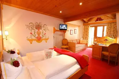 a bedroom with a large bed and a living room at Hotel Al Sonnenhof in San Vigilio Di Marebbe