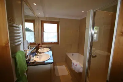 a bathroom with two sinks and a tub and a shower at Hotel Al Sonnenhof in San Vigilio Di Marebbe