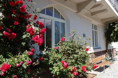 a woman sitting at a table in front of a house at Villa Quenz Family Suites in Ortisei