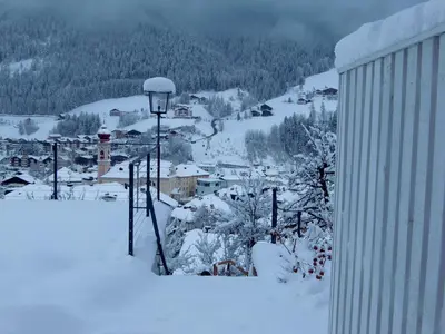 a building with people on the balcony in the snow at Villa Quenz Family Suites in Ortisei