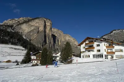 a group of people skiing in the snow in front of a building at Residence Villa Funtanes in Selva di Val Gardena