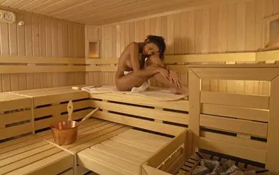 a woman is sitting in a sauna at Residence Villa Funtanes in Selva di Val Gardena