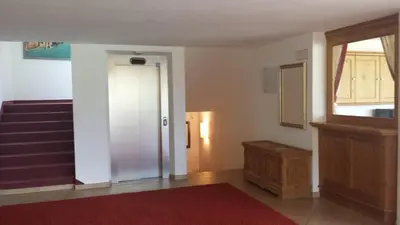 a hallway with a door and stairs with a red rug at Residence Villa Funtanes in Selva di Val Gardena