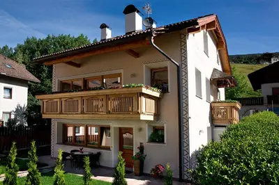 a large white house with a balcony and a table at Cesa Sule de Sot in Ortisei