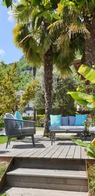 two benches sitting on a wooden deck under a palm tree at Ansitz Strengherrnhof in Caldaro