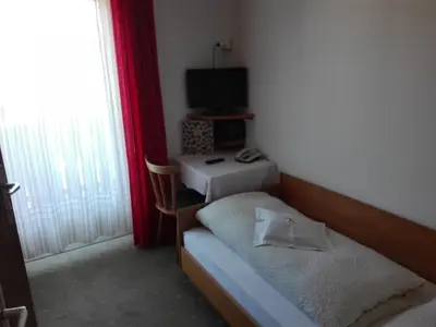 a small room with two beds and a television at Hotel Haselried in Tirolo