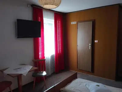 a room with a bed and a window with red curtains at Hotel Haselried in Tirolo