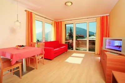 a living room with a red couch and a television at Hotel Haselried in Tirolo