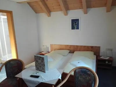 a bedroom with a bed and a table and chairs at Hotel Haselried in Tirolo