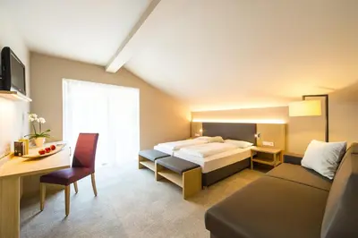 a bedroom with a bed and a desk and a couch at Hotel CampingPark Steiner in Laives